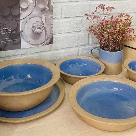 Bowls and plates mugs with glossy cornflower glaze contrasting with stone texture