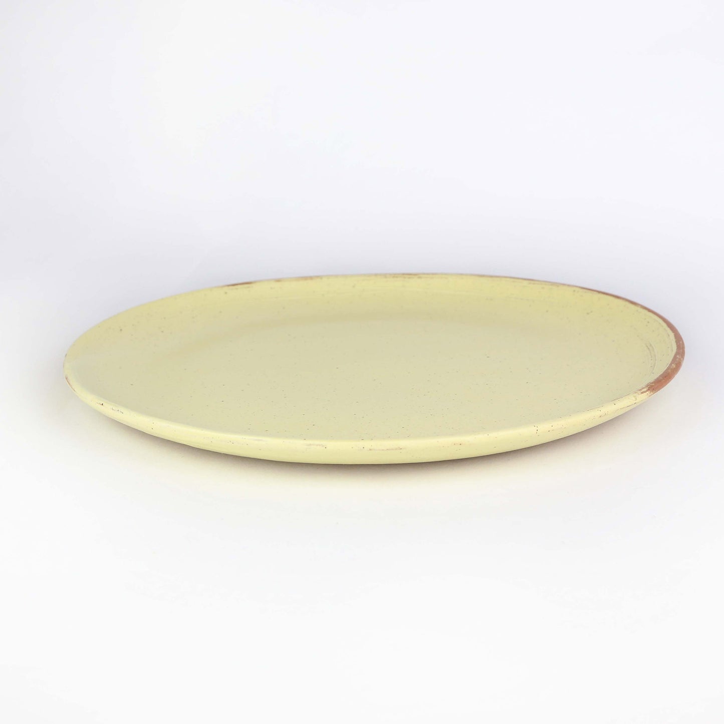 side on view of handmade ceramic dinner plate from Thailand yellow and natural clay