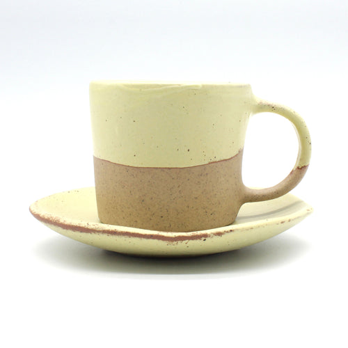 Side on view of beautiful handmade ceramic double espresso cup and saucer from Thailand, yellow and natural clay rustic look