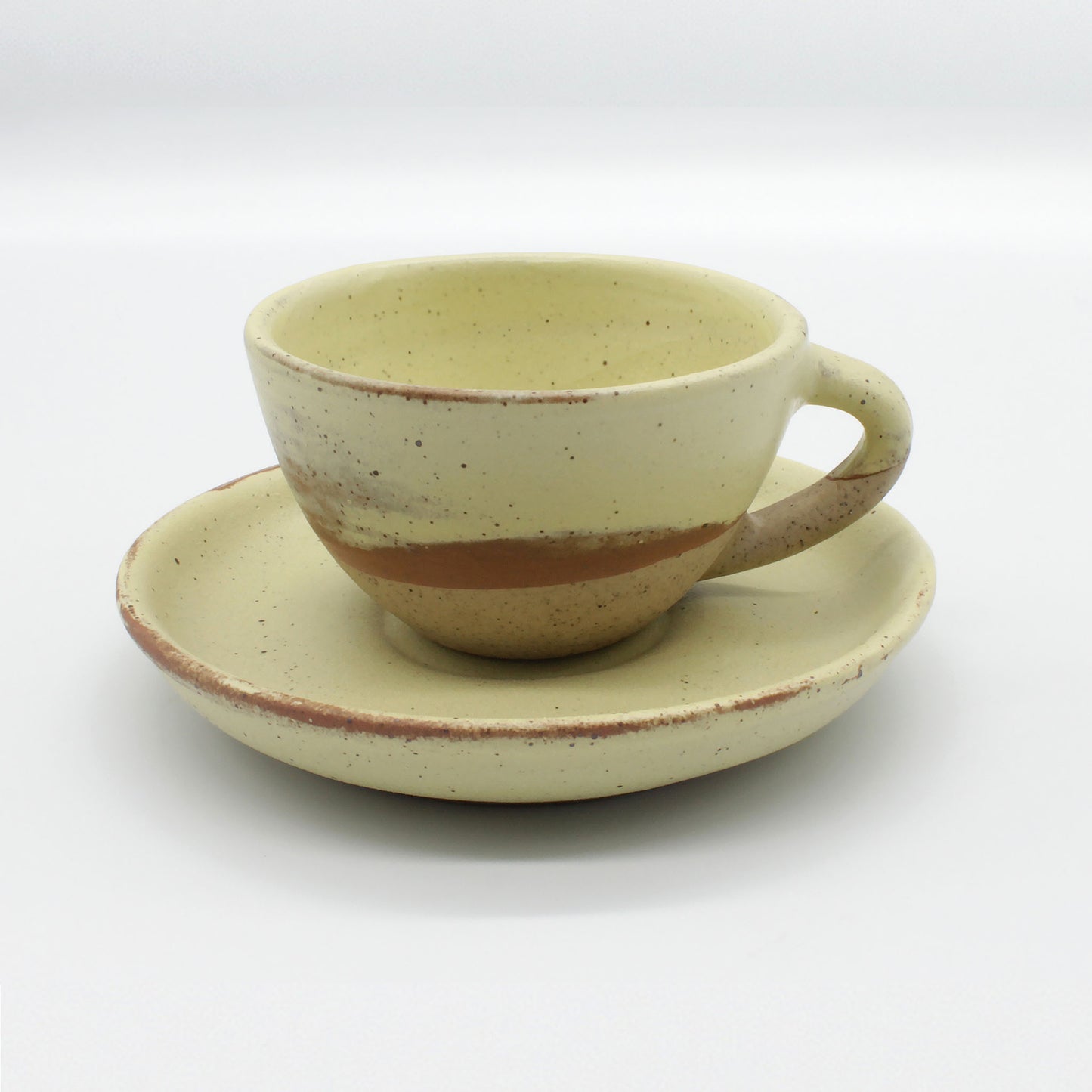 Side on view of beautiful handmade espresso cup and saucer from Thailand, yellow and natural clay rustic look