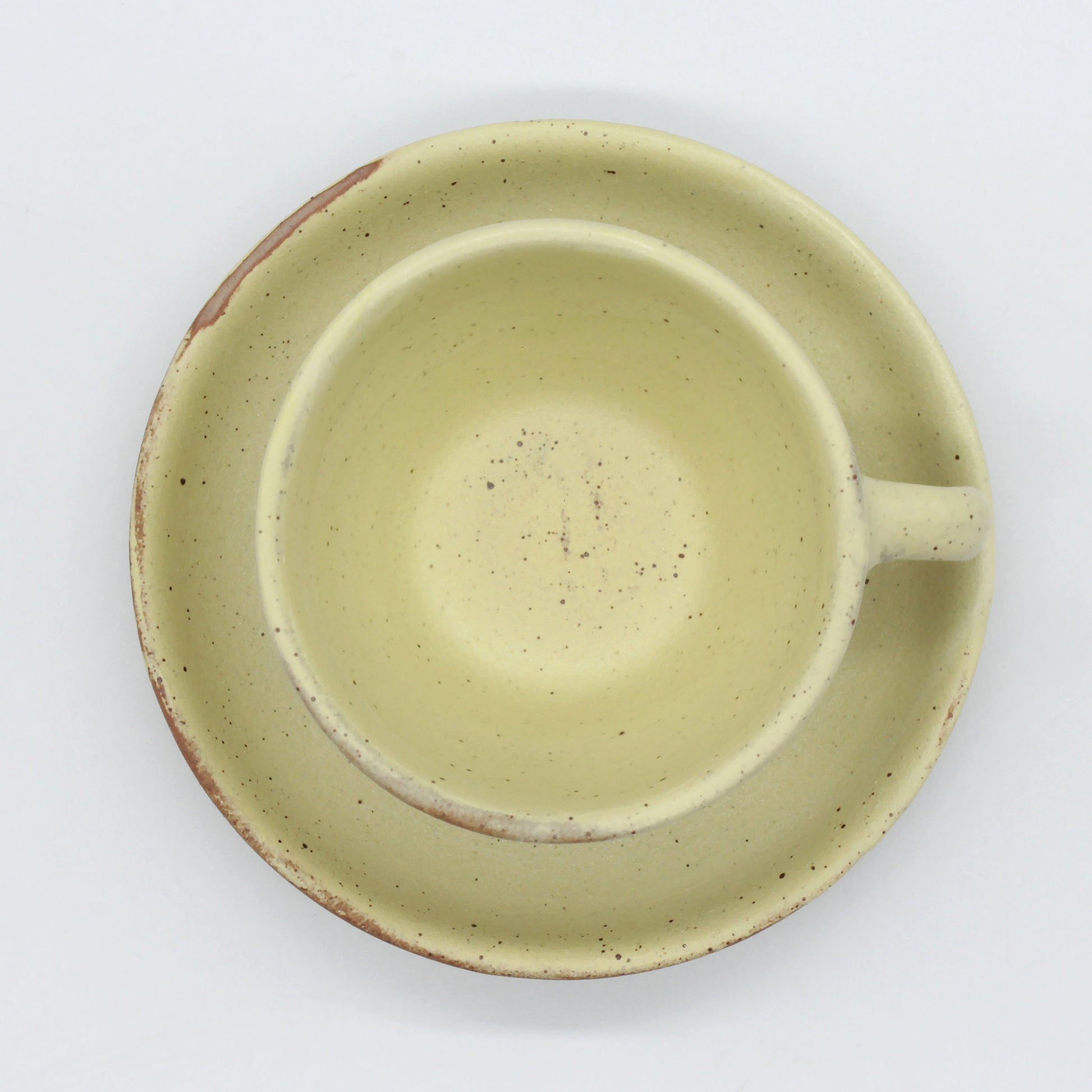 Top view of beautiful handmade espresso cup and saucer, yellow and natural clay speckled rustic