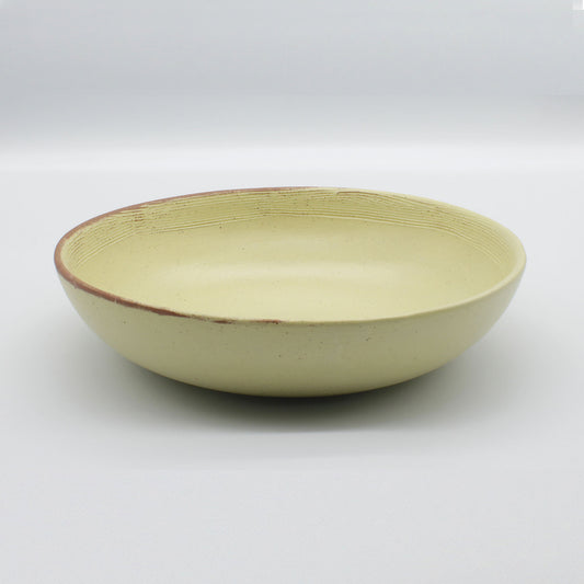 Side on view of beautiful handmade pasta bowl from Thailand, yellow and natural clay speckled rustic