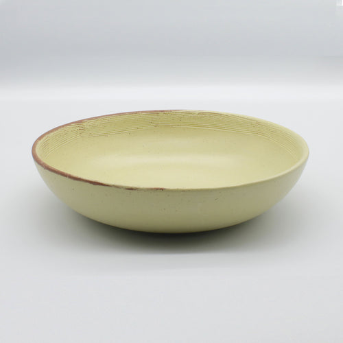 Side on view of beautiful handmade pasta bowl from Thailand, yellow and natural clay speckled rustic