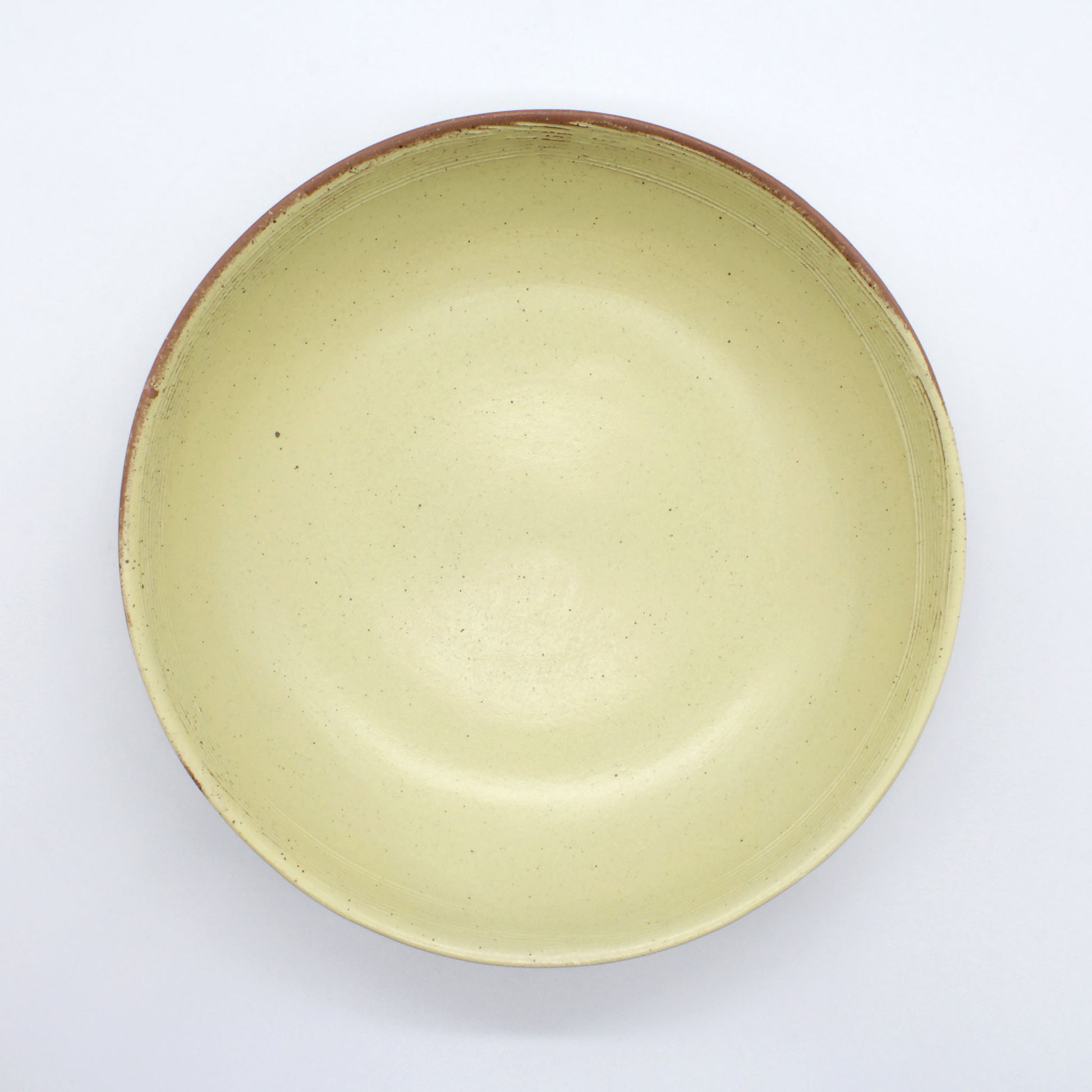 Top view of beautiful handmade pasta bowl from Thailand, yellow and natural clay speckled rustic look