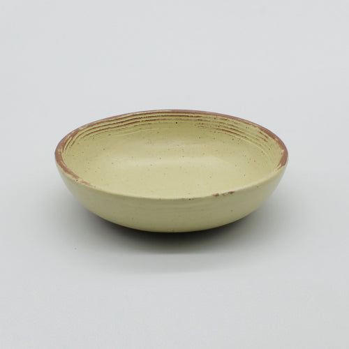 Side view of handmade ceramic sauce bowl from Thailand, yellow and natural speckled clay rustic