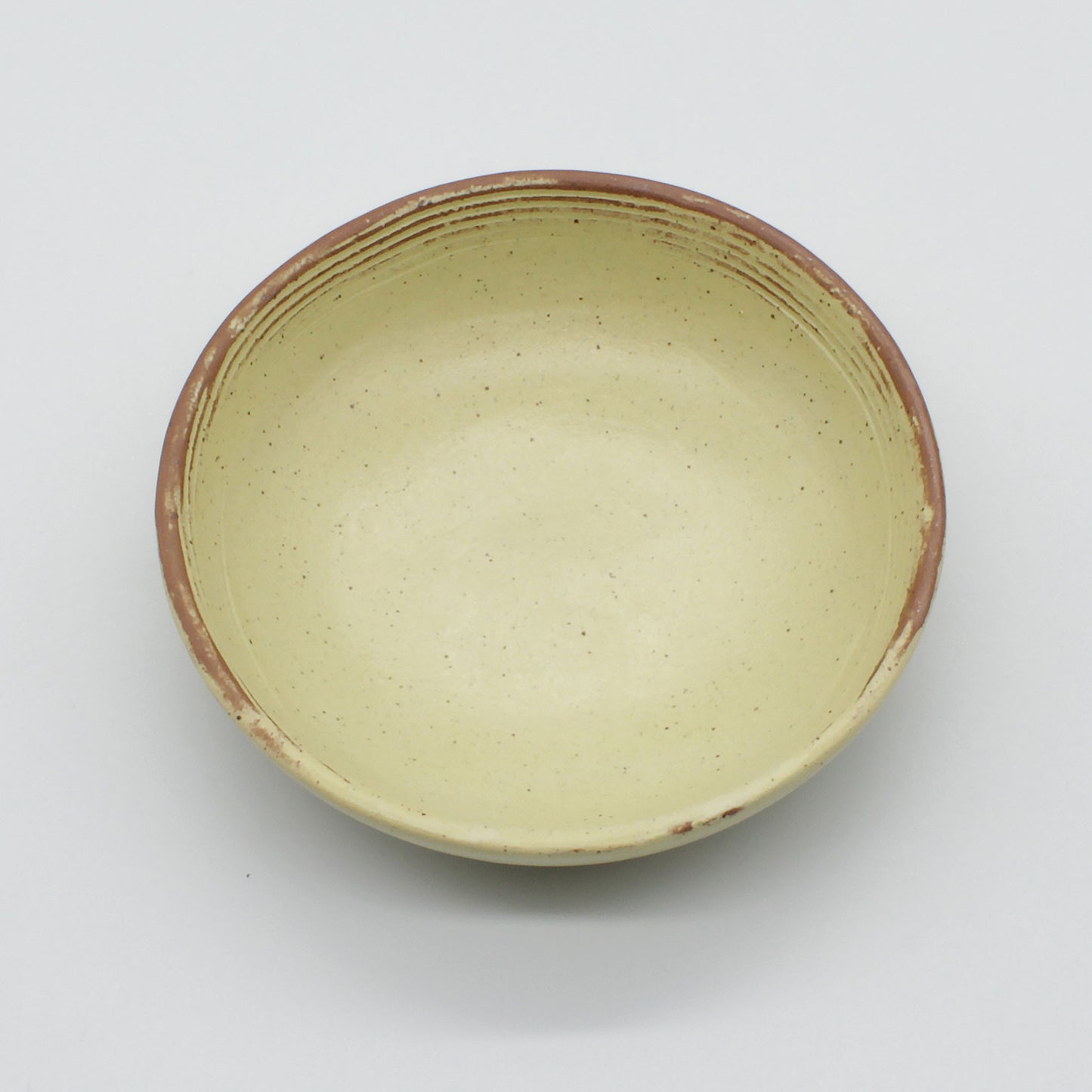 Top view of beautiful handmade sauce bowl on a white background. Yellow and natural clay rustic look