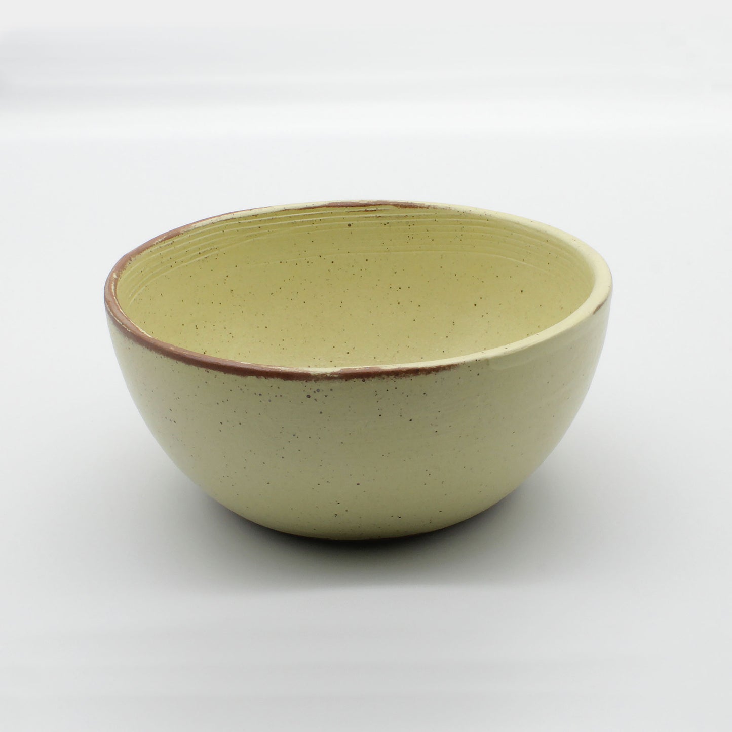 Side on view of handmade ceramic soup bowl from Thailand, yellow and natural clay rustic