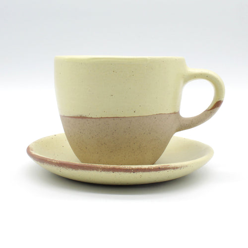 Side on view of beautiful handmade ceramic tea set, cup and saucer from Thailand. Yellow and natural clay rustic