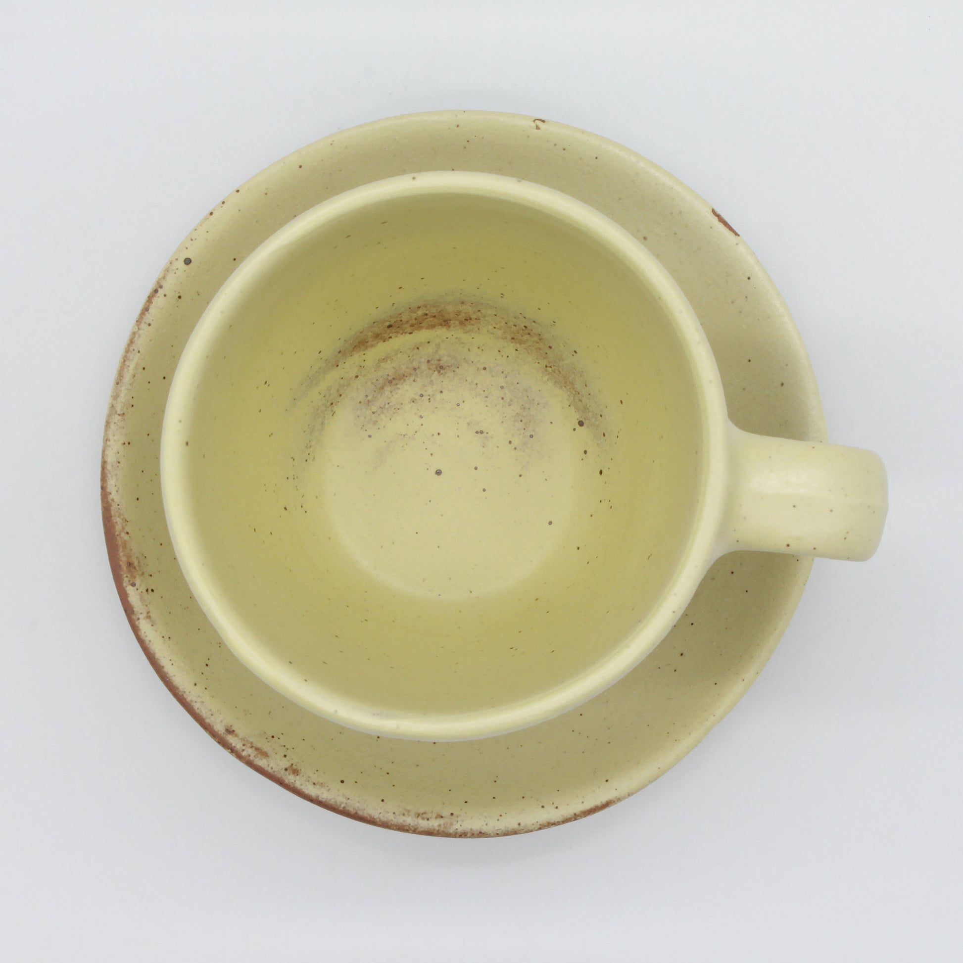 Top view of beautiful handmade ceramic tea cup and saucer from Thailand. Yellow and natural clay