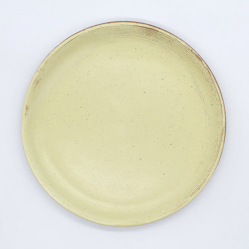 Top view of a beautiful handmade ceramic side plate from Thailand, yellow with natural clay rustic