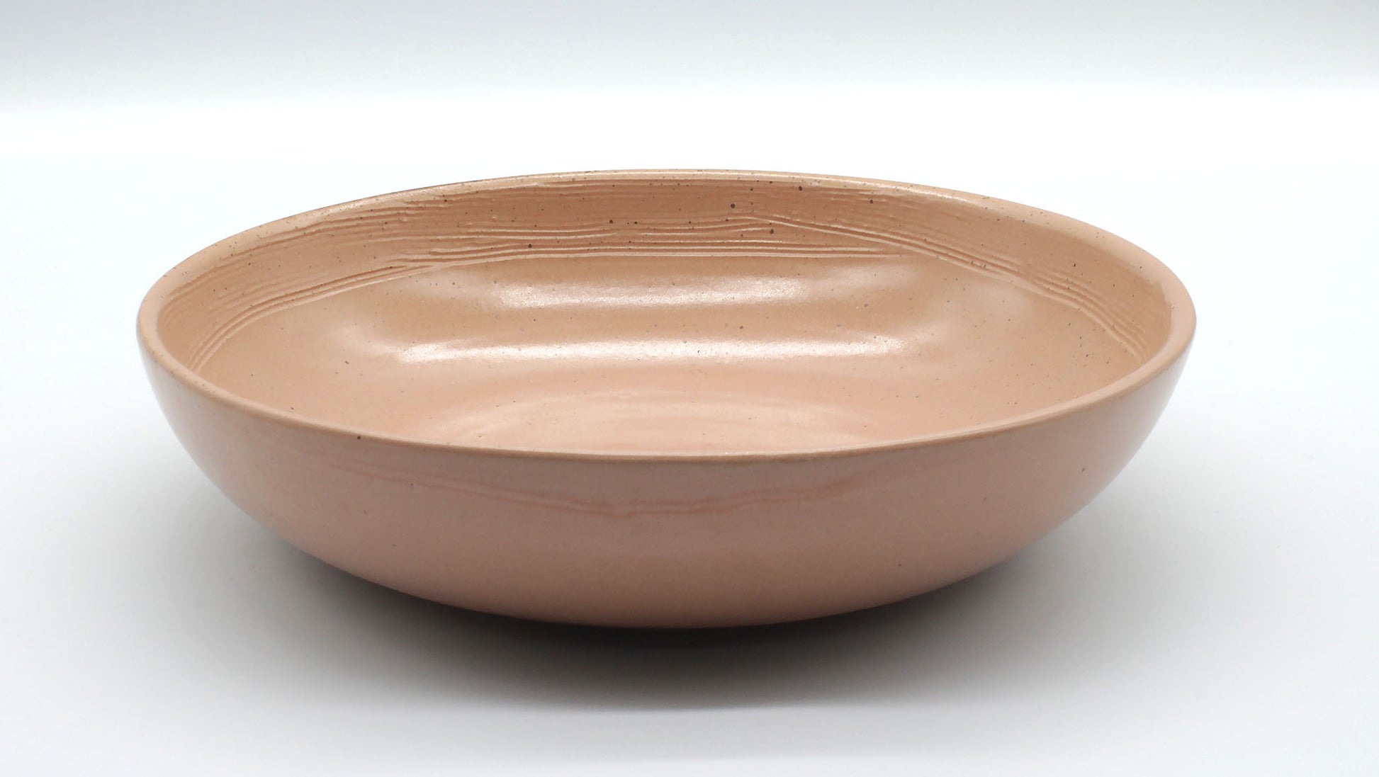 Side on view of handmade ceramic pasta bowl from Thailand. Pink, peach colour with natural clay, rustic natural look