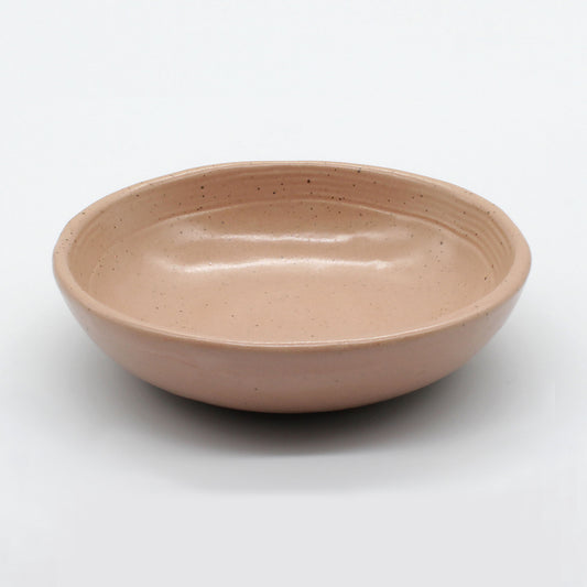 Side on view of beautiful handmade ceramic sauce dish from Thailand. Pink, peach colour with natural clay, rustic natural look