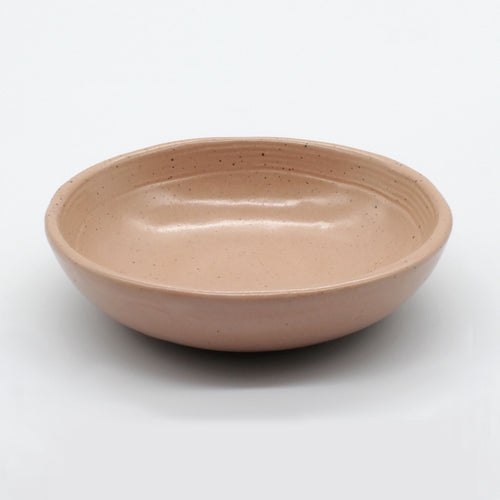 Side on view of beautiful handmade ceramic sauce dish from Thailand. Pink, peach colour with natural clay, rustic natural look