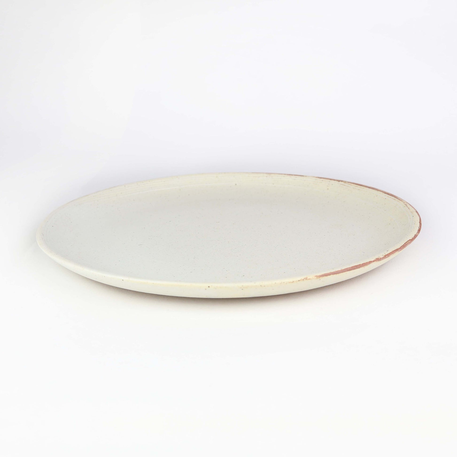 Handmade ceramic Lotus Dinner Plate -side view. Antique white in colour with black speckles